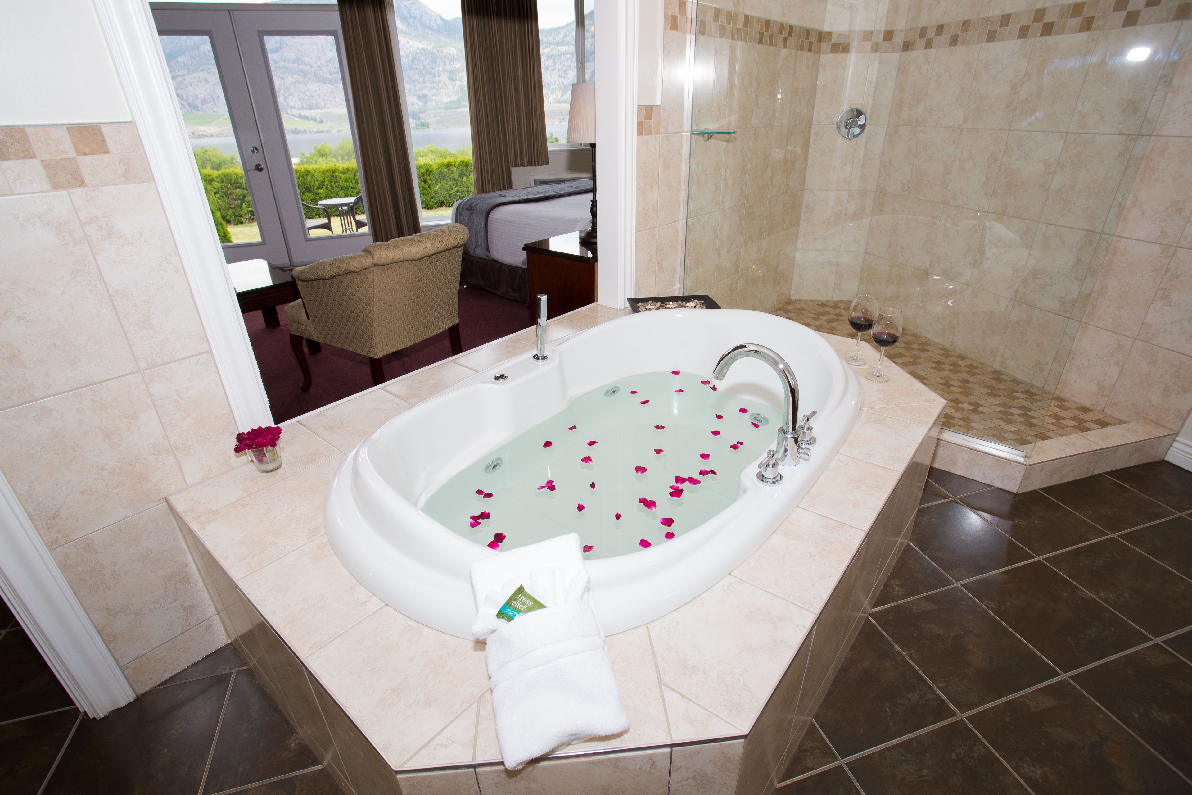 A bathroom with a bathtub, shower, and a view of a mountainous landscape.