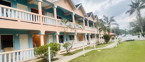 Un hotel de varios pisos con balcones, un césped bien cuidado y un cielo despejado.