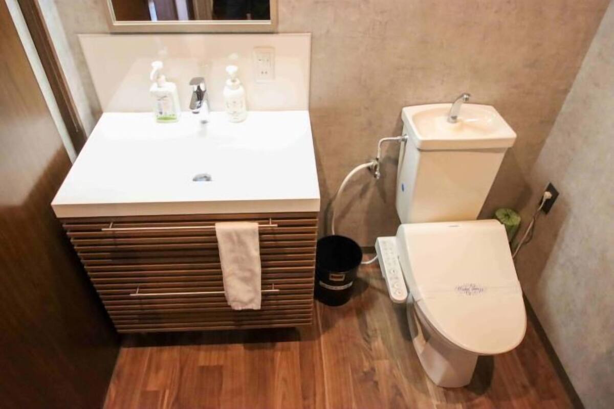 A bathroom with a sink, toilet, and a small trash bin.