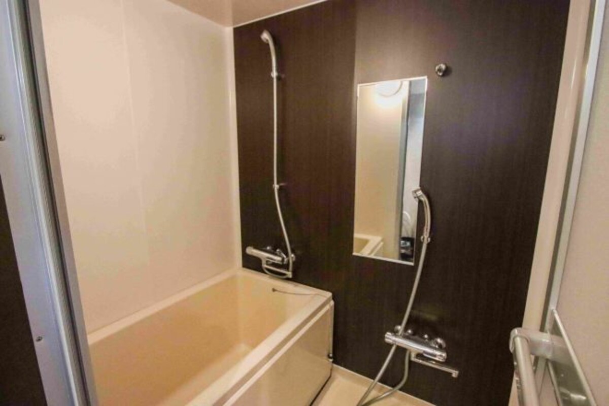 A bathroom with a bathtub, a shower, a mirror, and a door.