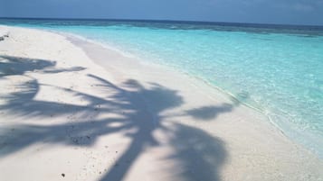 Ein Strand mit klarem türkisblauem Wasser und weißem Sand.