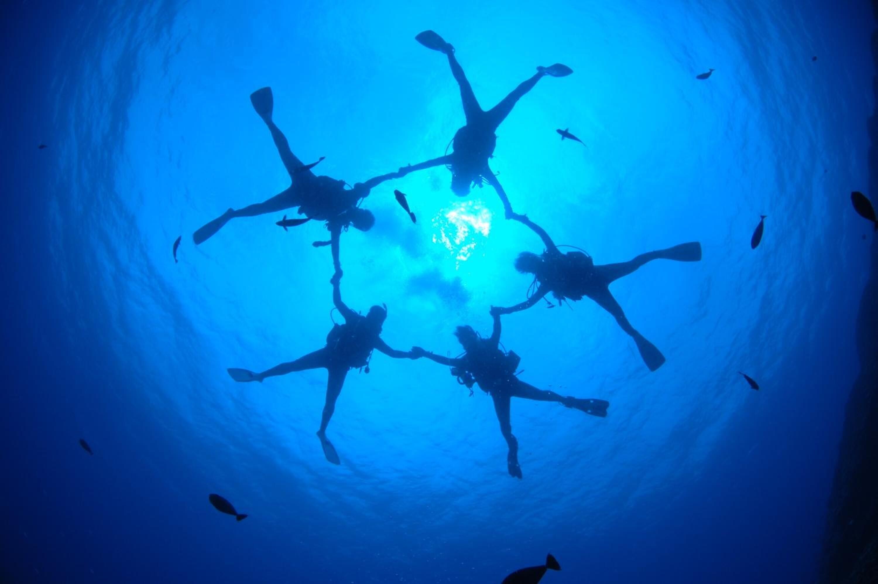 A diver in a blue-lit tunnel with a central light source.