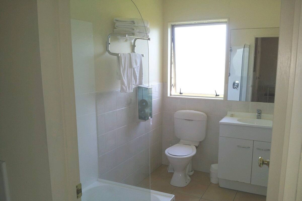 A bathroom with a toilet, sink, and a window.
