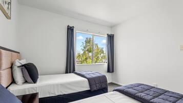 A room with two single beds, a headboard, and a window with curtains.