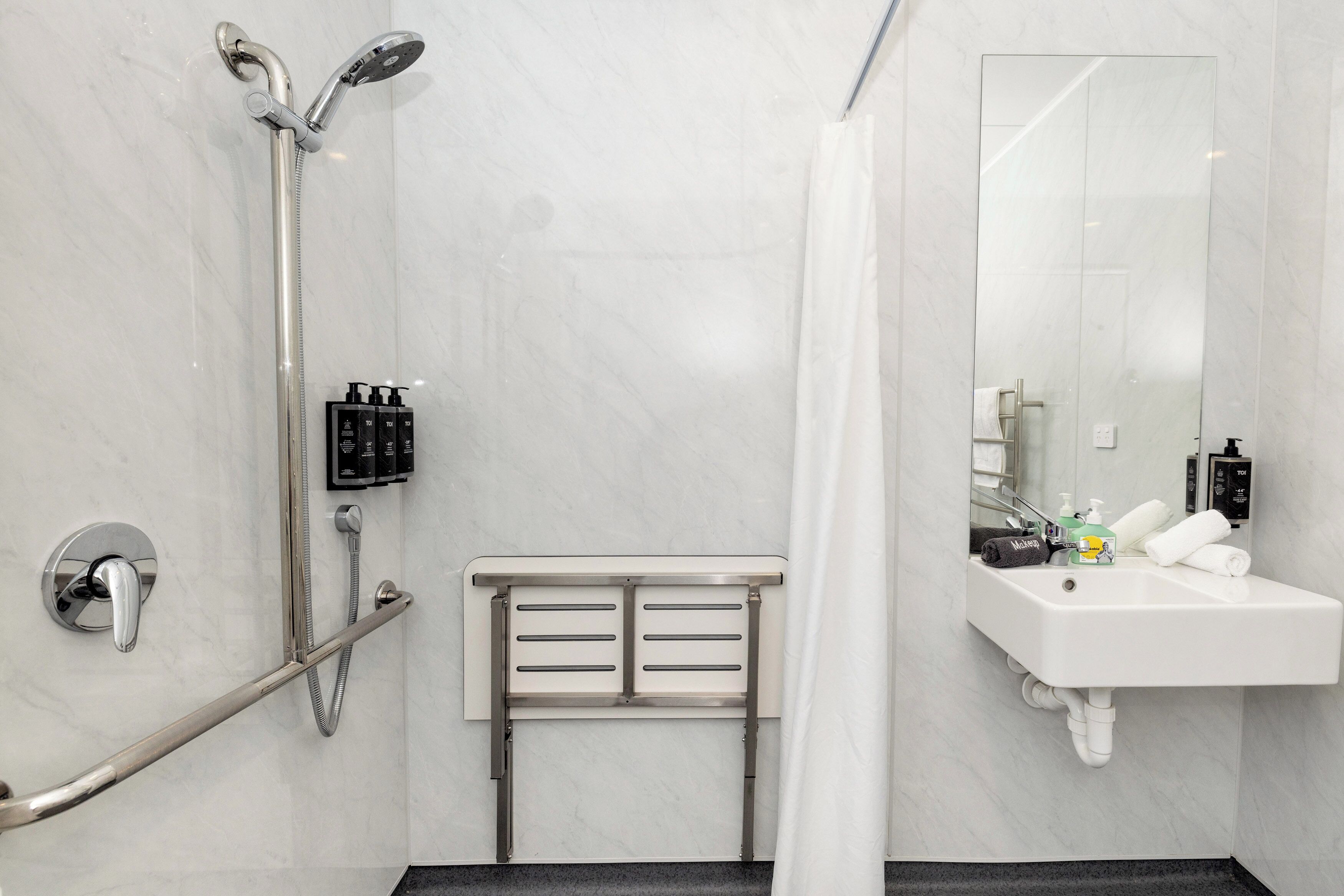 Een moderne badkamer met douche, toilet en wastafel.
