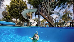 Una piscina con tobogán y plataforma de madera.
