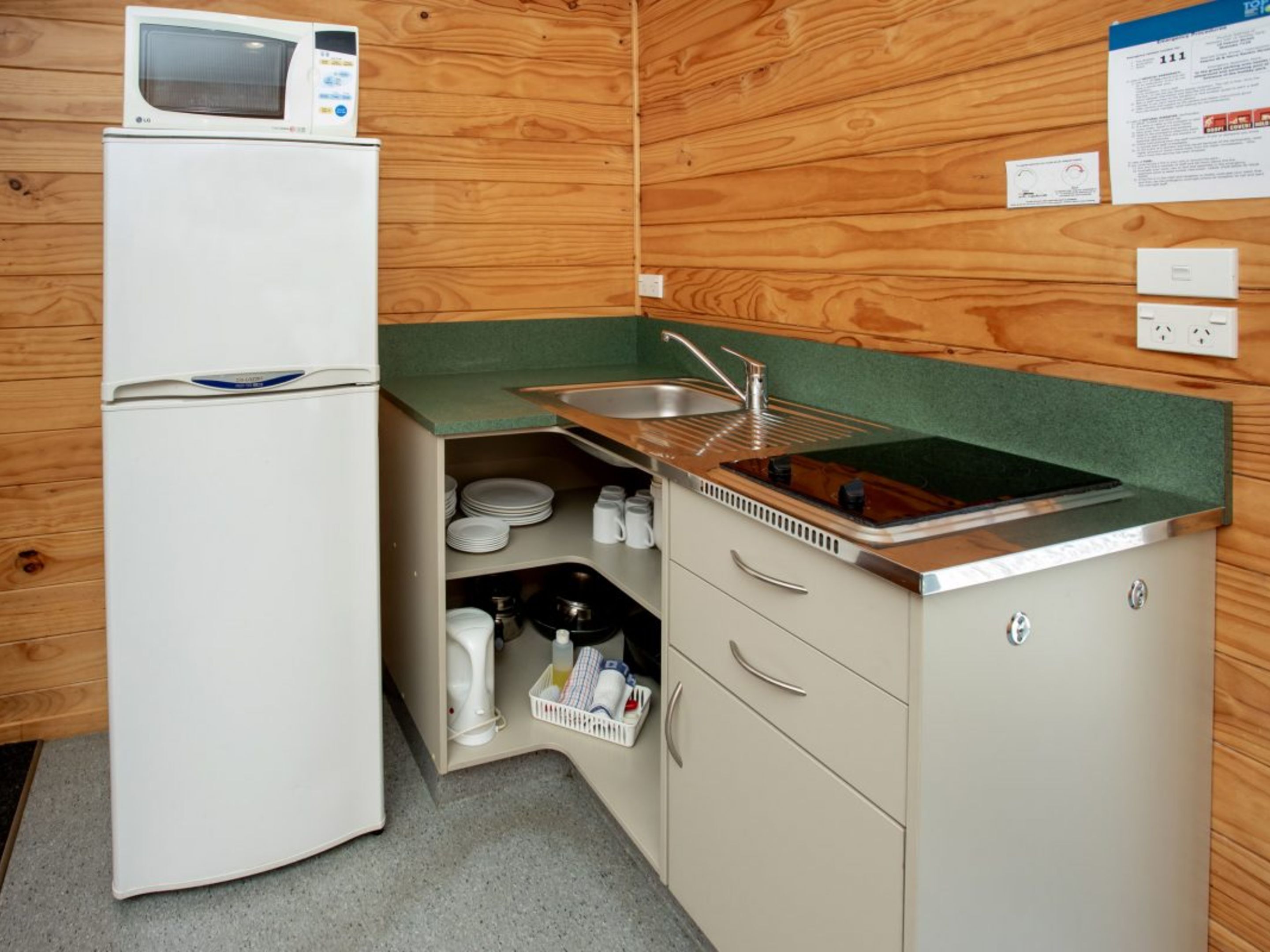 A compact kitchenette with a microwave, sink, and storage cabinets.