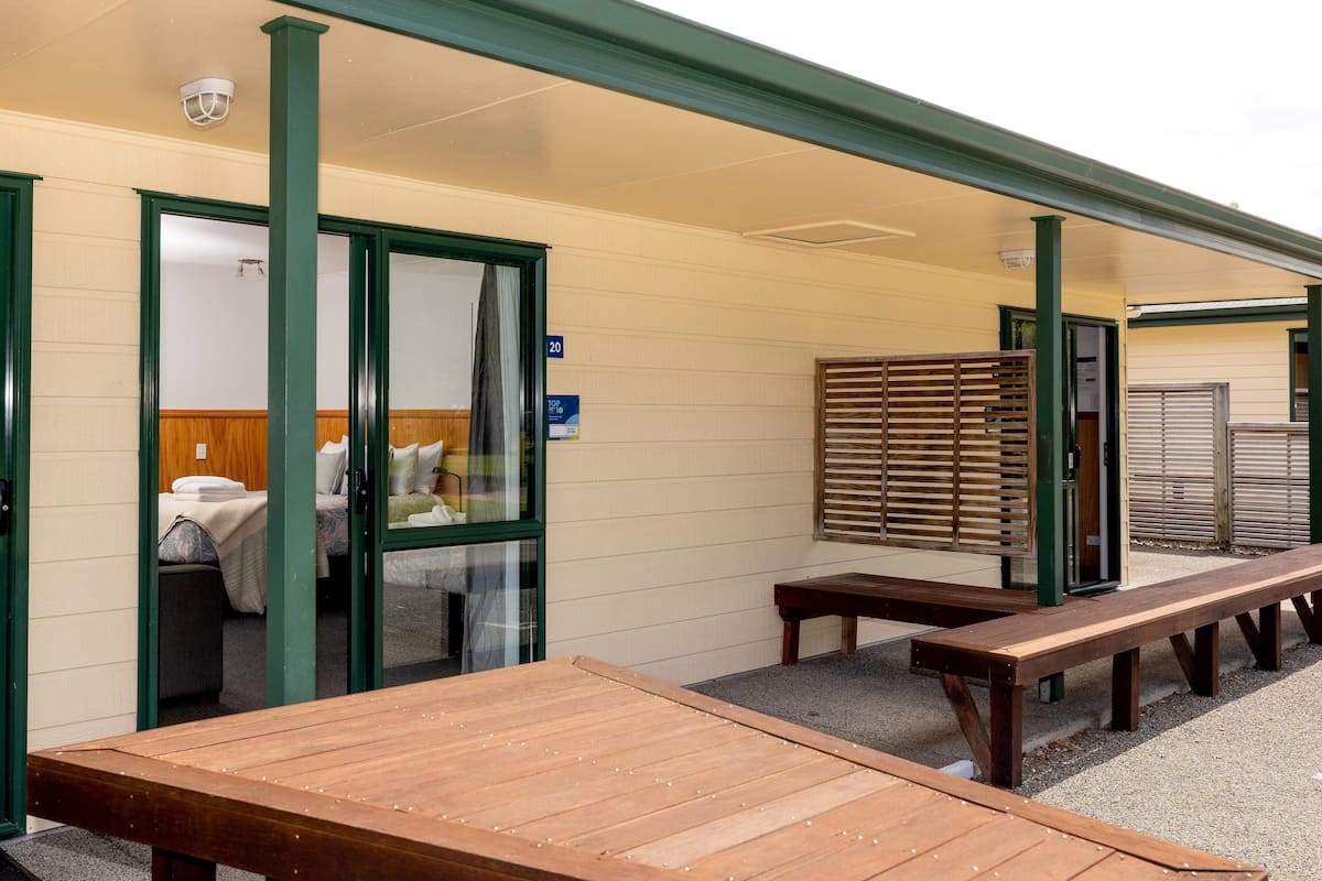 Une chambre d’hôtel avec un lit, un banc et une table en bois à l’extérieur.