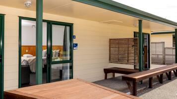Habitación de hotel con cama, banca y mesa de madera en el exterior.