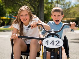Dos niños montando una bicicleta con una placa de matrícula 142.