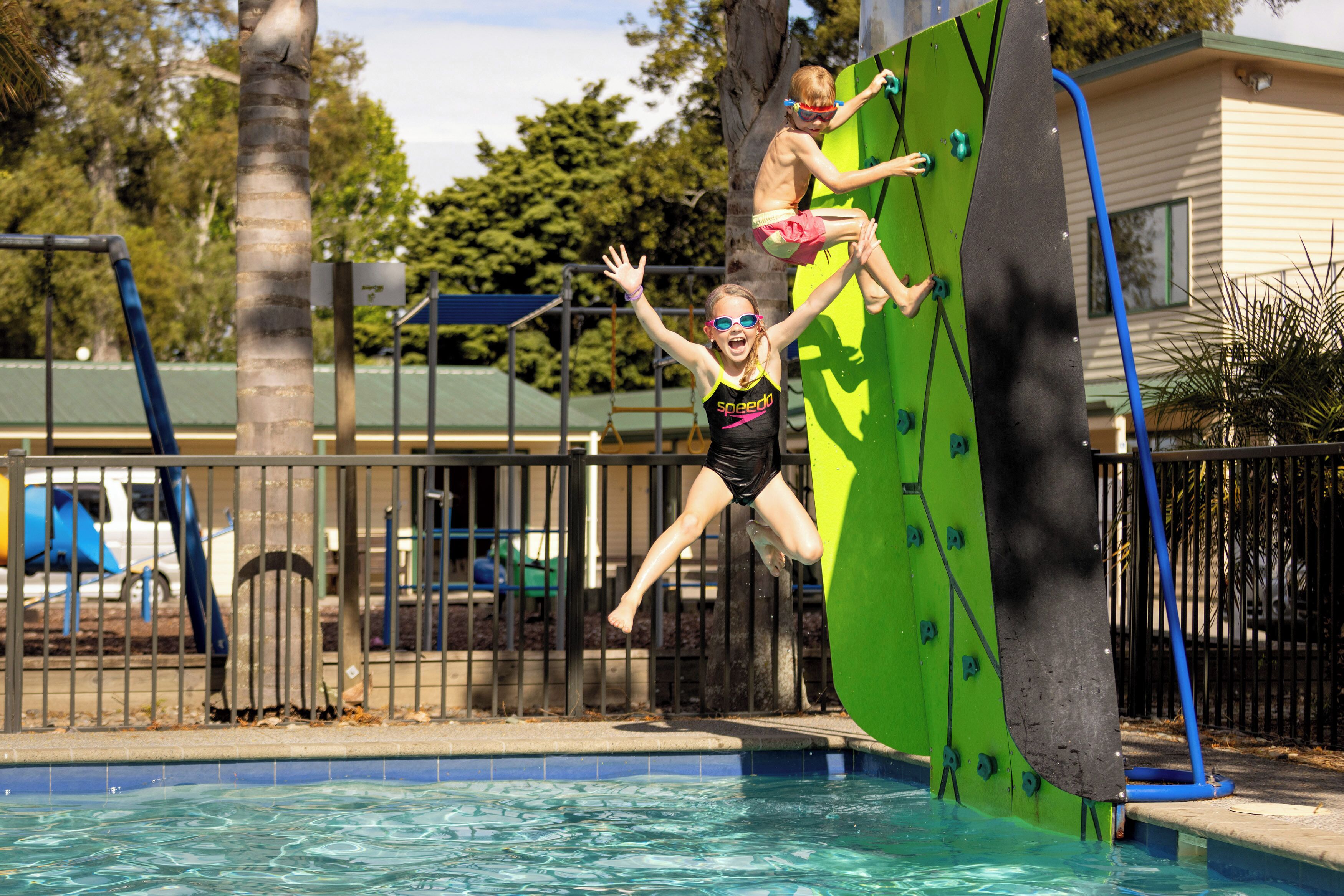 A pool with a diving board and a fence.