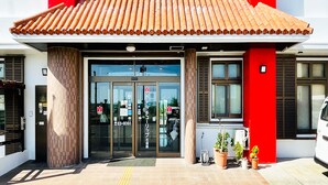 Ein Gebäude mit roter und weißer Fassade, einem Ziegeldach und einem Glas Eingang.