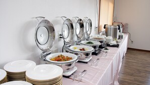 Ein Buffet mit mehreren Servierstationen, darunter Schalen mit Speisen und gestapelten Tellern.