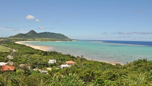 Eine Küstenlandschaft mit Strand, Berg und einigen Gebäuden.