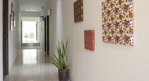 Un couloir avec une plante en pot, une porte et trois œuvres d’art accrochées au mur.