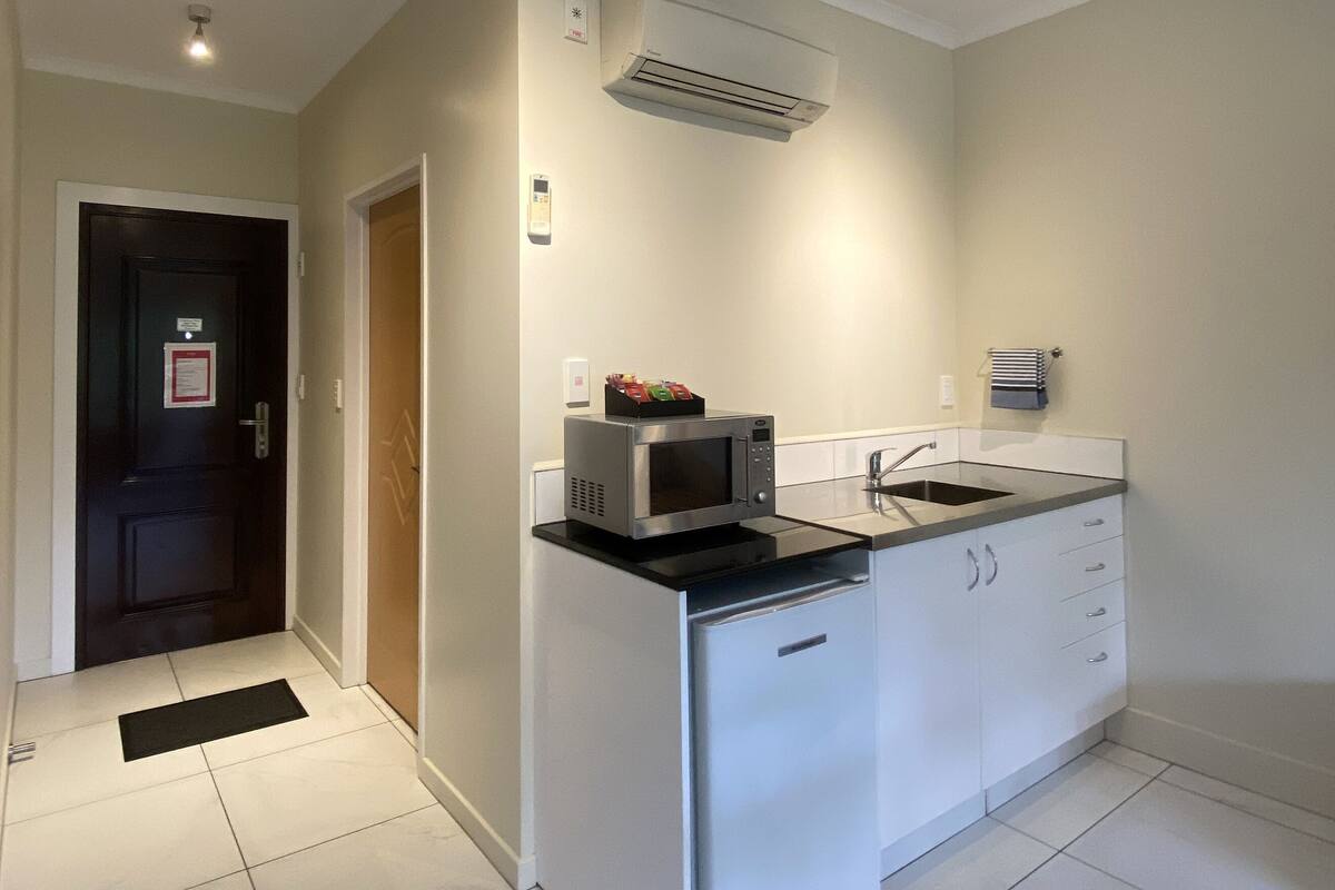 A compact kitchen with white cabinets, a microwave, and a sink.