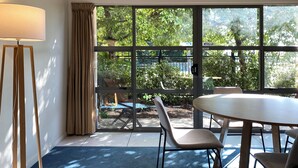 A room with a large window, a table, chairs, and a floor lamp. - Saxton Lodge (Nelson)