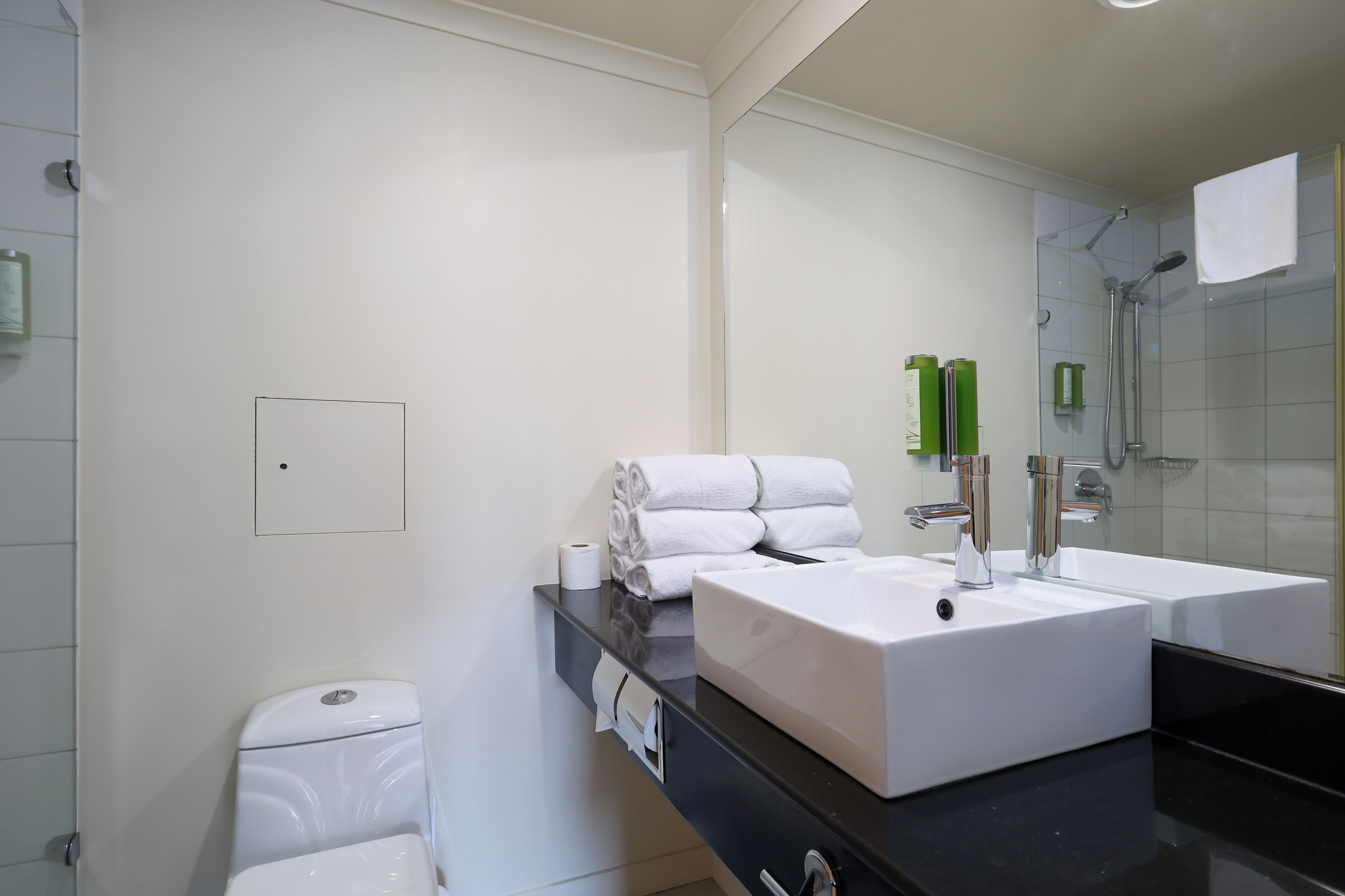 Un baño moderno con un lavamanos blanco, un espejo y una zona de ducha.