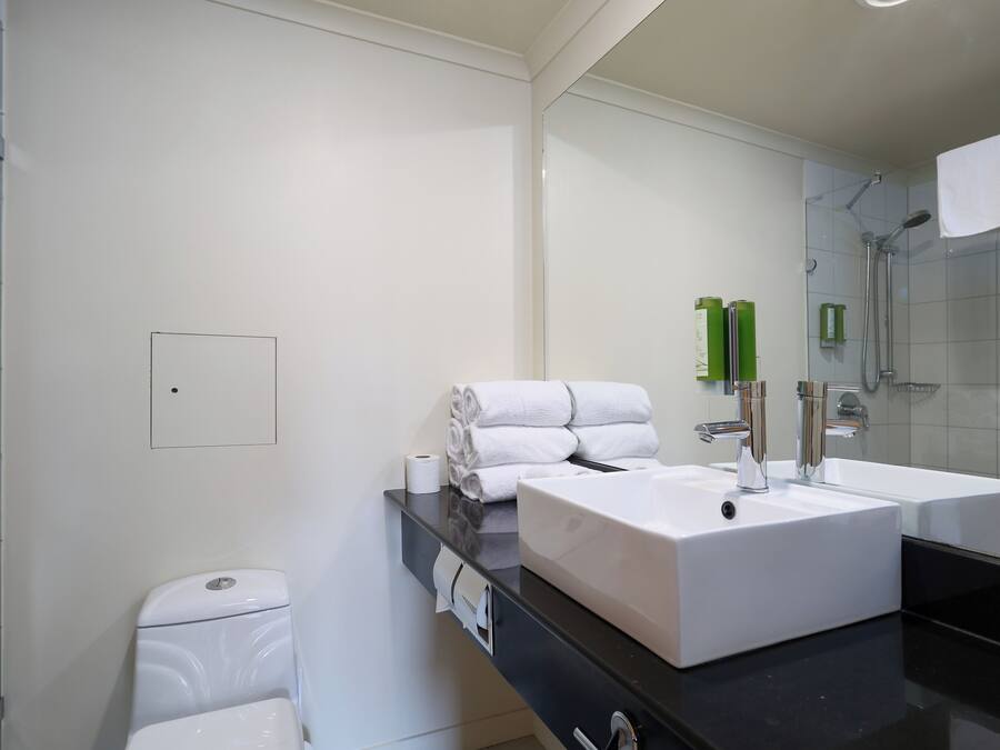 Un baño moderno con un lavamanos blanco, un espejo y una zona de ducha.
