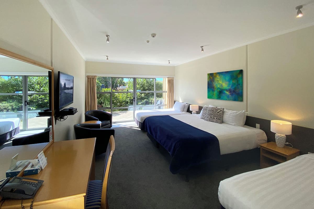 A hotel room with a bed, a desk, a chair, a TV, and a painting.