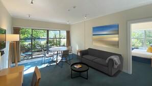 A spacious living room with a large window, a gray sofa, a coffee table, and a painting on the wall. - Saxton Lodge (Nelson)