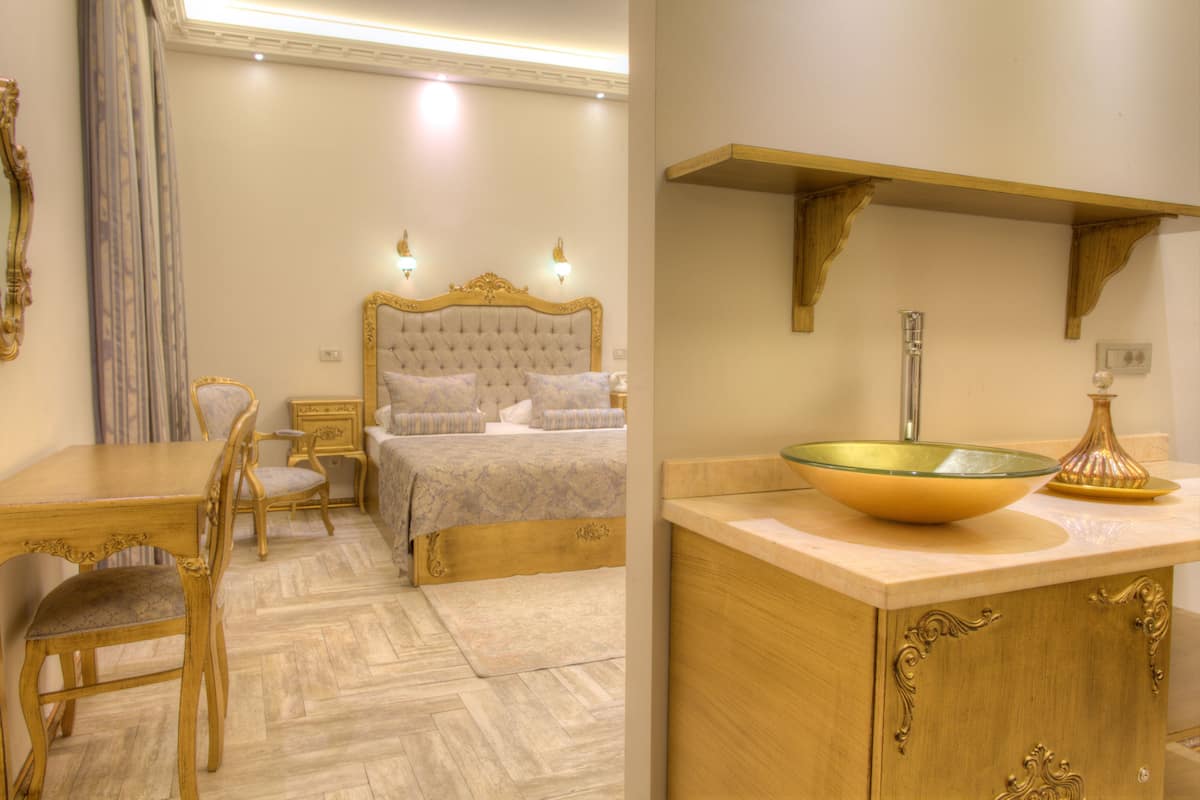 A bedroom with a large bed, bedside tables, and a wooden desk with chairs.