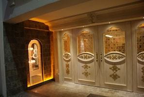 A set of ornate doors with intricate designs and a stone wall with a glass door. - Elegance Residence (Istanbul)
