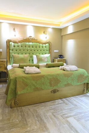 A large bed with a green upholstered headboard, a matching green bedspread, and two bedside tables with lamps. - Elegance Residence (Istanbul)