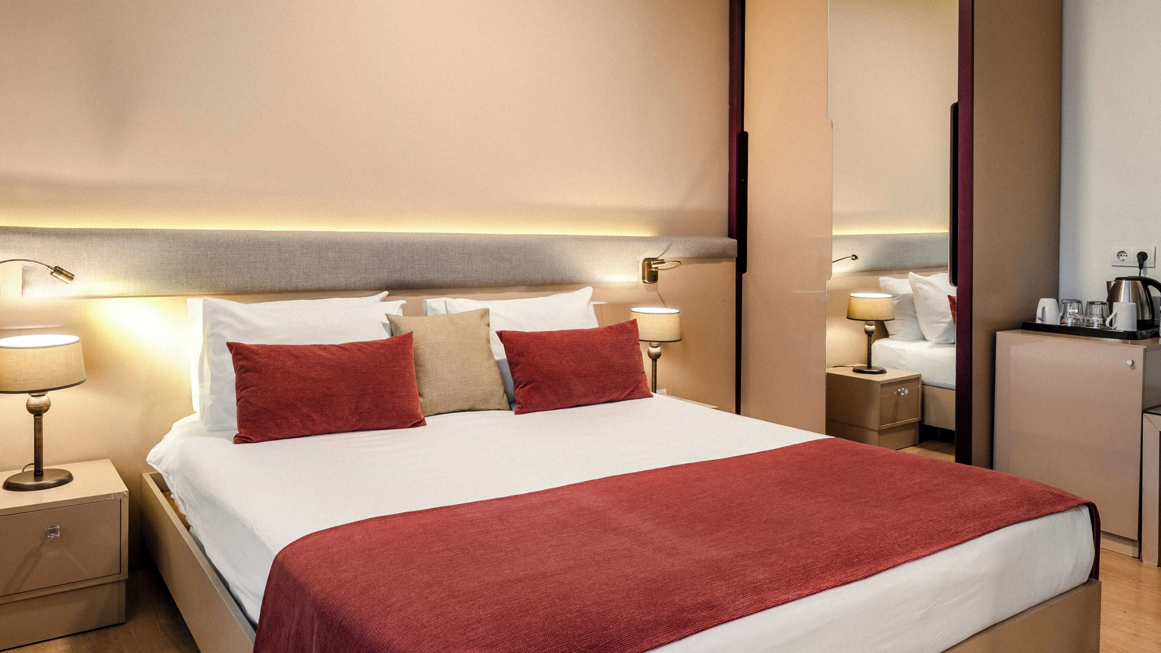Une chambre d’hôtel comprenant un lit, des tables de chevet, des lampes, une commode, un miroir et une armoire.