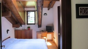 A bedroom with a bed, a desk, a TV, and a window. - Casa Alpina Don Guanella (Macugnaga)