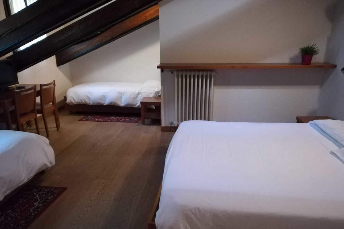 A bedroom with two beds, a desk, and a chair.