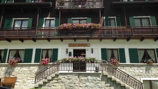 A multi-story building with balconies adorned with flowers, a stone staircase, and a sign reading "CASA ALPINA". - Casa Alpina Don Guanella (Macugnaga)