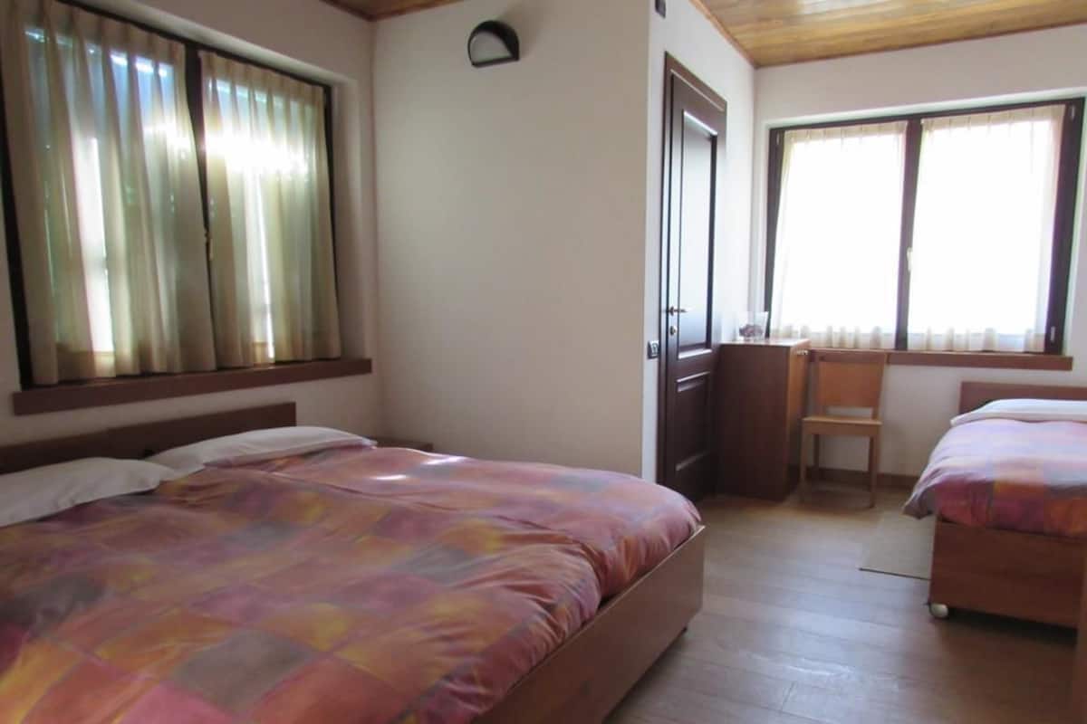 A bedroom with two beds, a desk, and a chair.