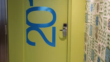 A door with the number 201 painted in blue, a keypad lock, and a tiled wall with a geometric pattern.