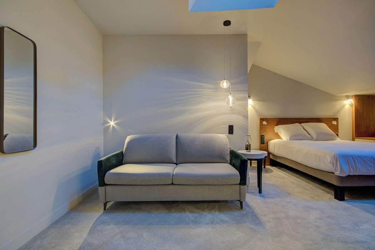A modern bedroom with a sofa, a bed, and a nightstand.