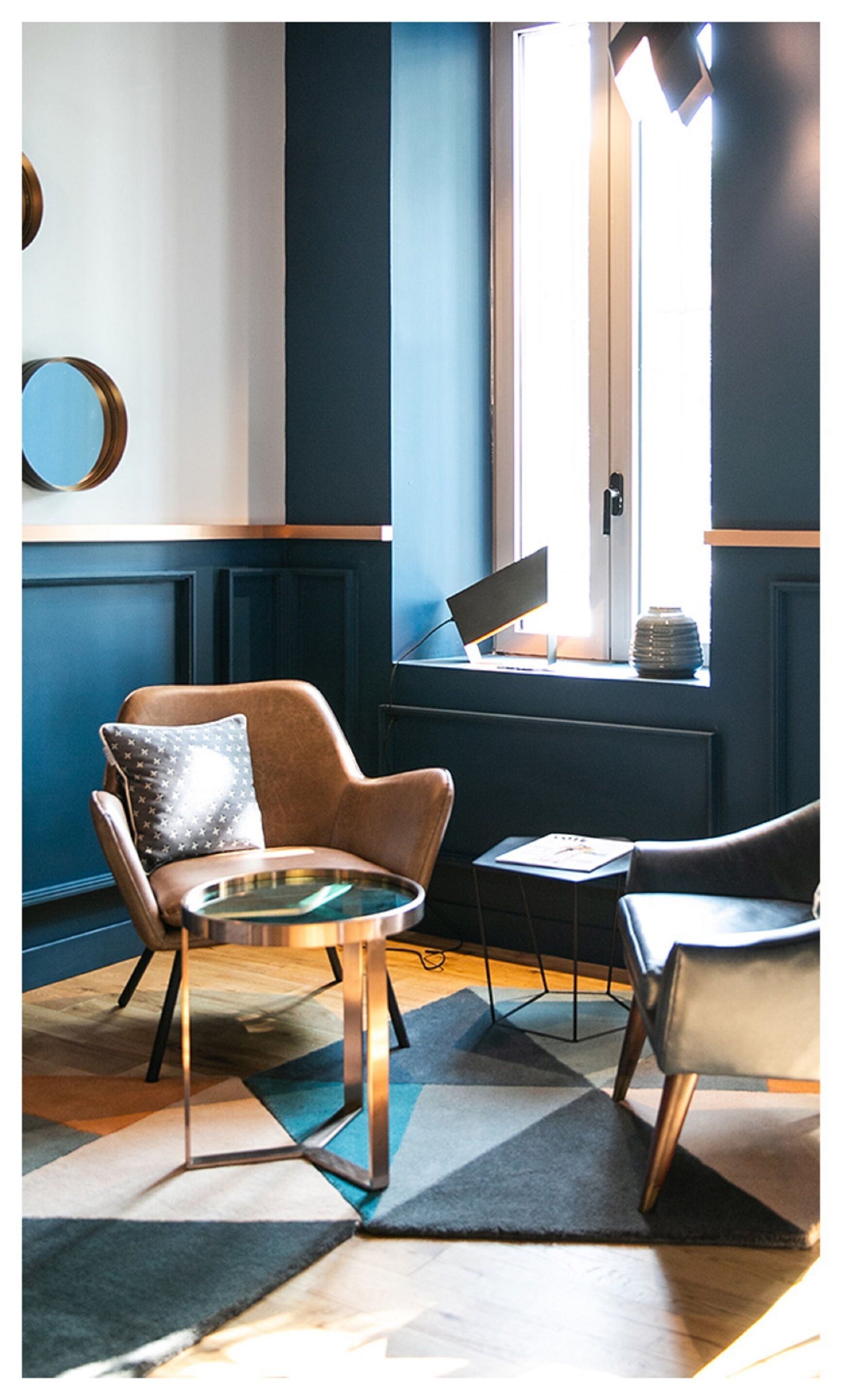 Una habitación moderna con un sillón de cuero marrón, una mesita redonda y un ordenador portátil sobre el alféizar de una ventana.