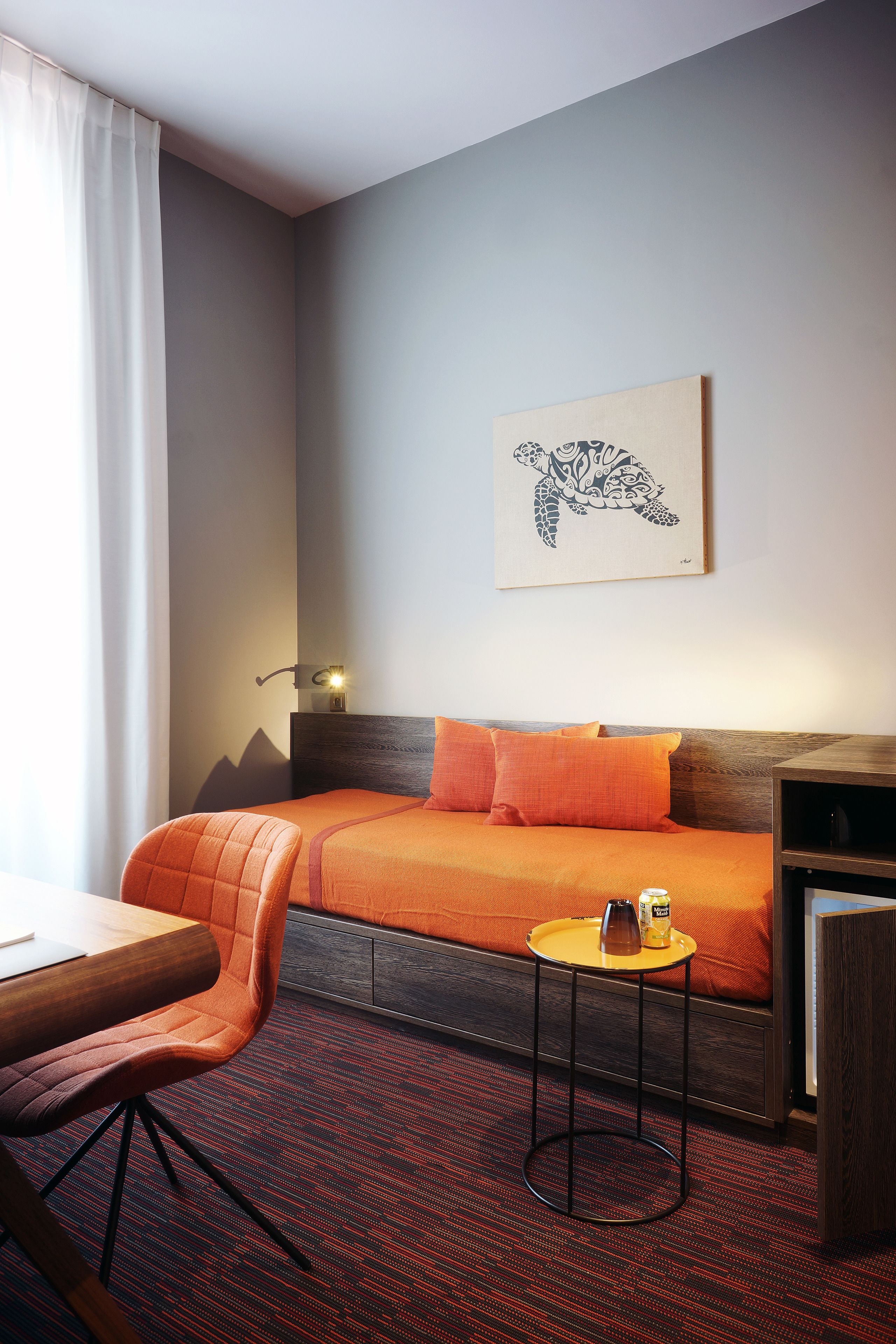 Une chambre d’hôtel avec un lit, une chaise, une petite table et un tableau au mur.