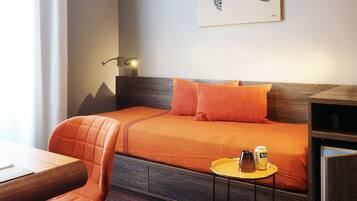 Une chambre d’hôtel avec un lit, une chaise, une petite table et un tableau au mur.