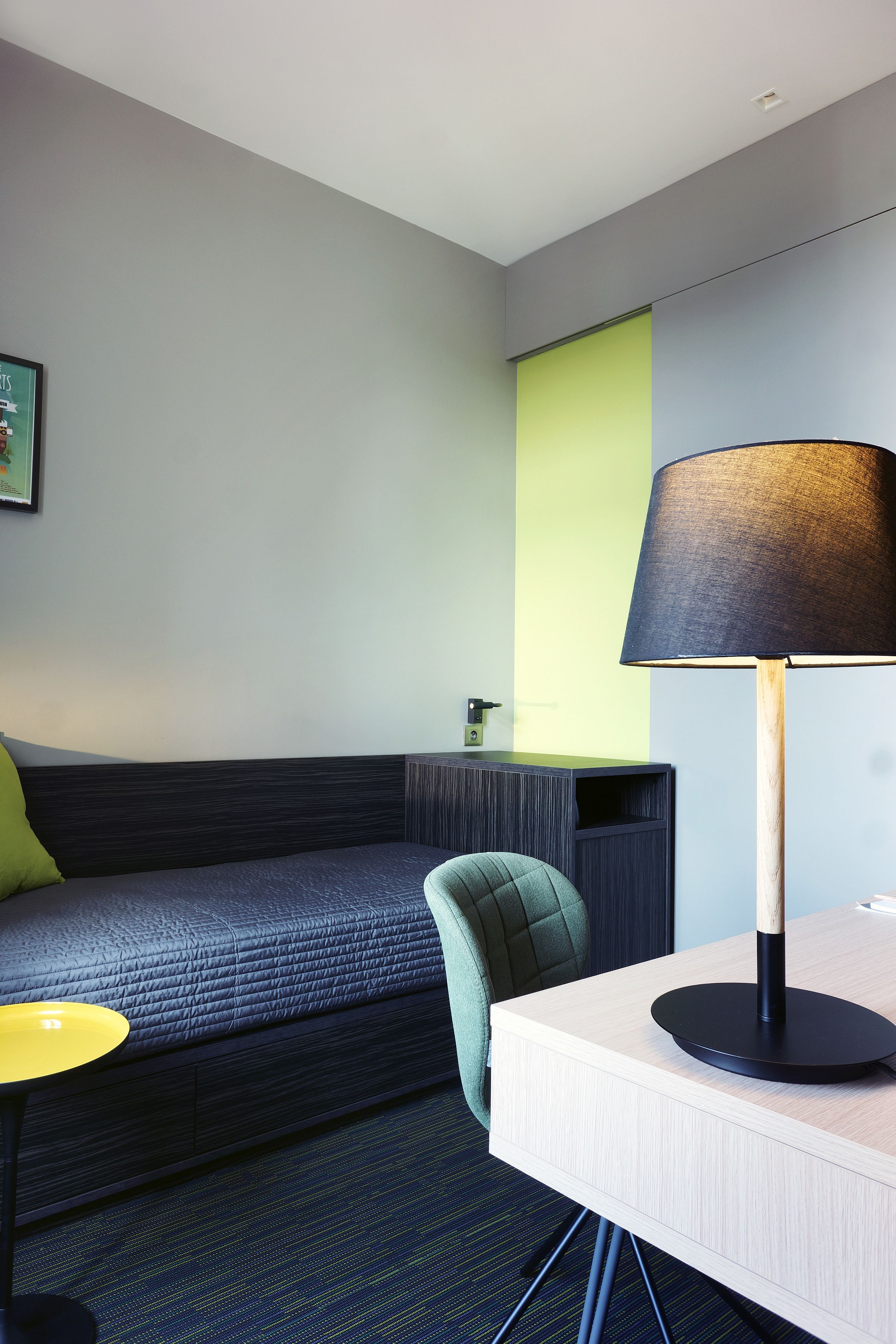 Une chambre d’hôtel moderne équipée d’un lit, d’un bureau, d’une chaise et d’une lampe.