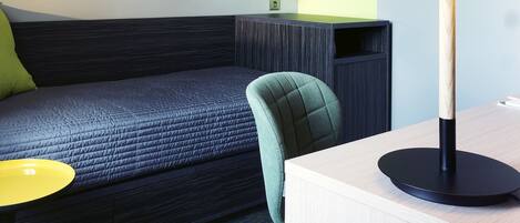 Une chambre d’hôtel moderne équipée d’un lit, d’un bureau, d’une chaise et d’une lampe.