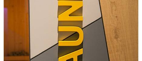 A sign with the word "SAUNA" in bold, yellow letters on a grey background.