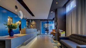 Een moderne hotellobby met een receptiebalie, zithoek en een vloer met een patroon.