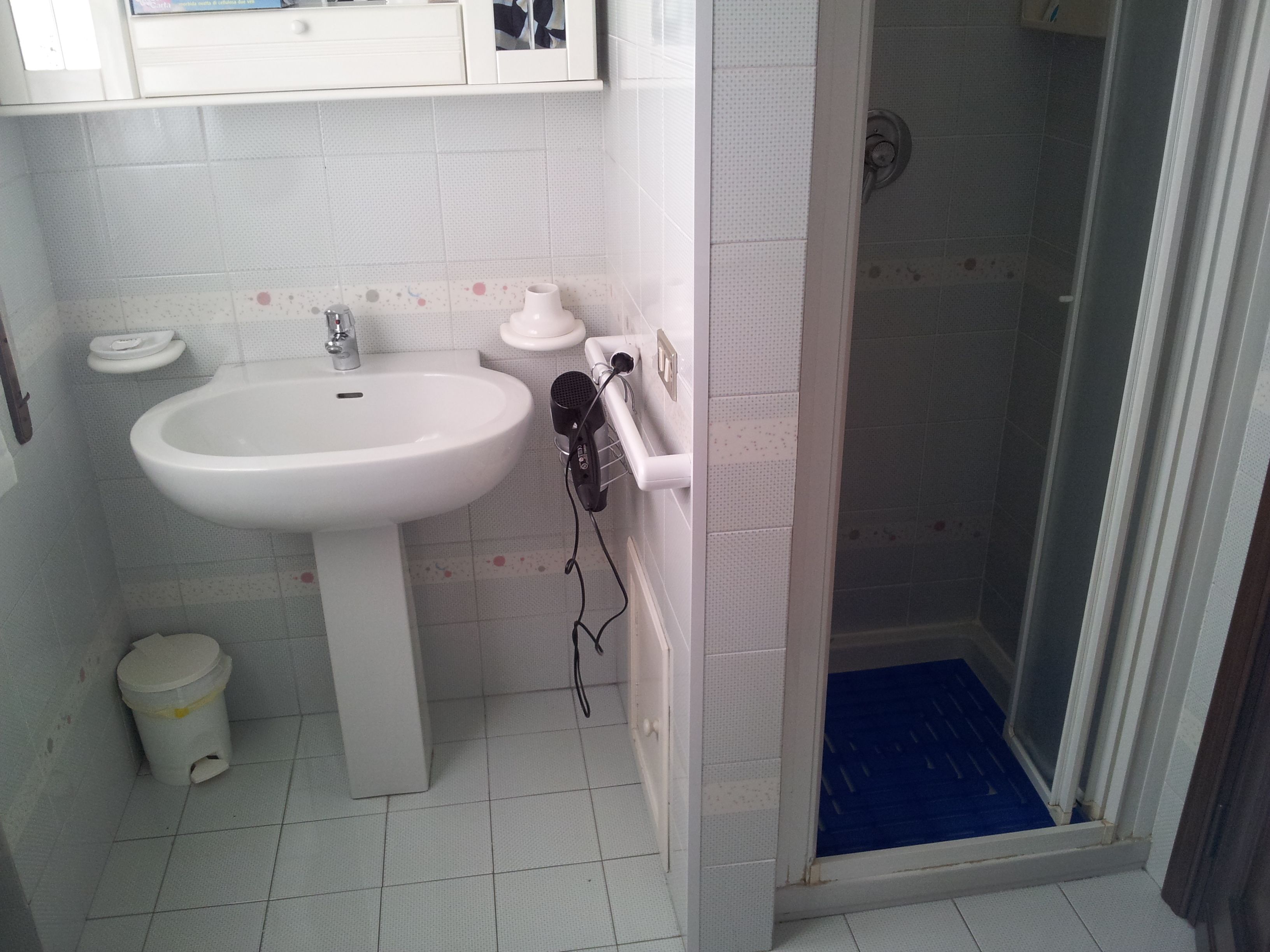 Une salle de bain avec un lavabo blanc, des toilettes et un espace douche.
