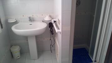 Une salle de bain avec un lavabo blanc, des toilettes et un espace douche.