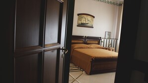 Une chambre à coucher avec un lit en bois, une table de chevet, un tableau encadré au mur et une porte donnant sur une autre pièce.