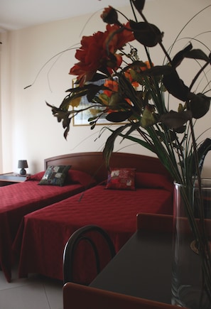 Een hotelkamer met twee bedden, een eettafel en een vaas met bloemen.