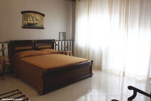 Un dormitorio ordenado con una cama grande, una mesita de noche, una lámpara y un cuadro en la pared.