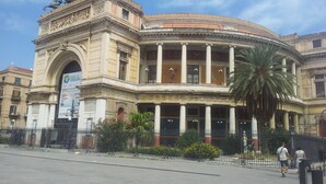 Un bâtiment historique à l’architecture classique, caractérisé par une entrée centrale en arc de cercle et des colonnes.