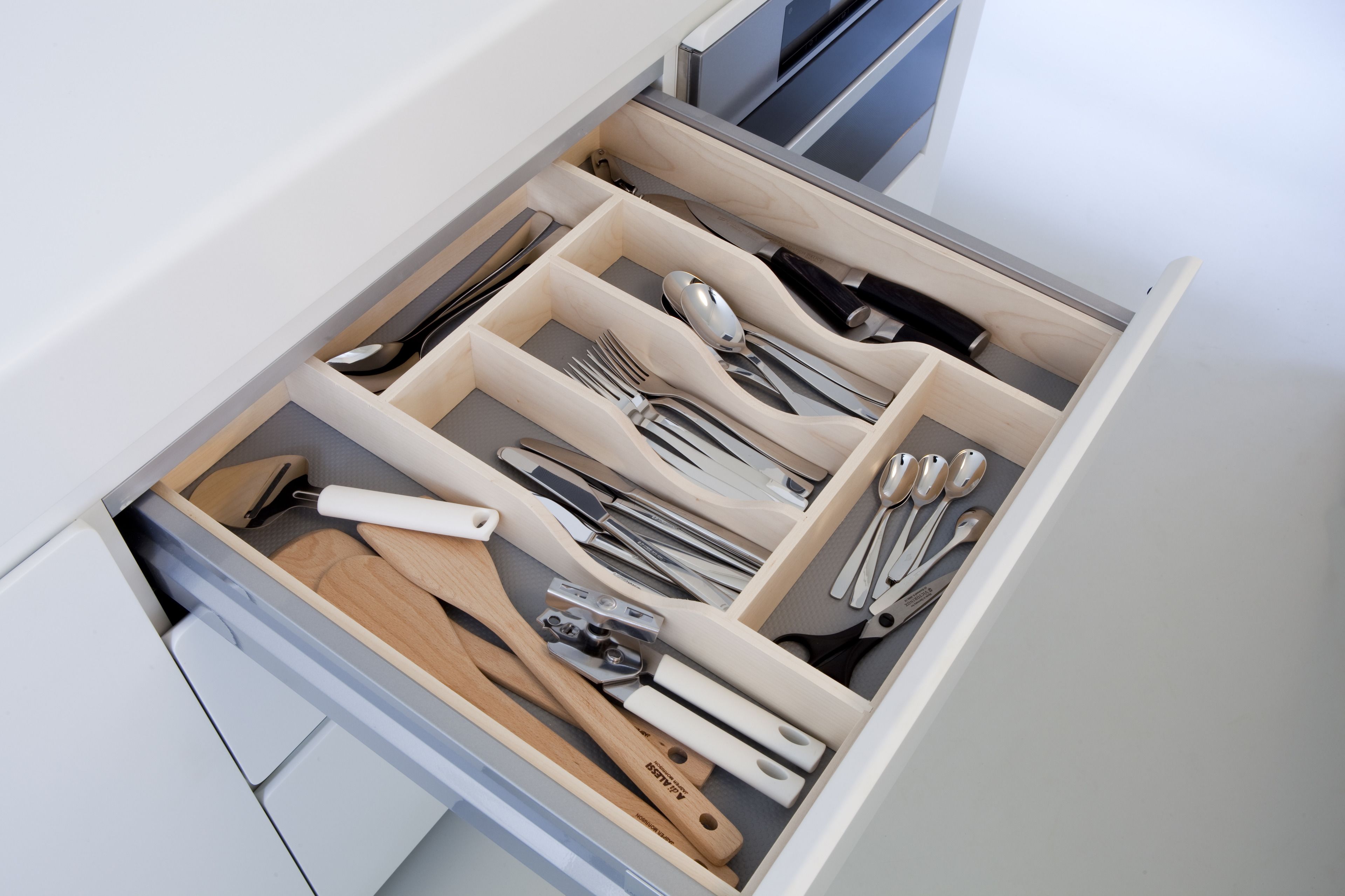 Un cajón con varios compartimentos que contiene diferentes utensilios de cocina.