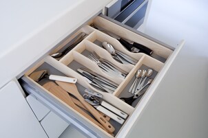 Un cajón con varios compartimentos que contiene diferentes utensilios de cocina.